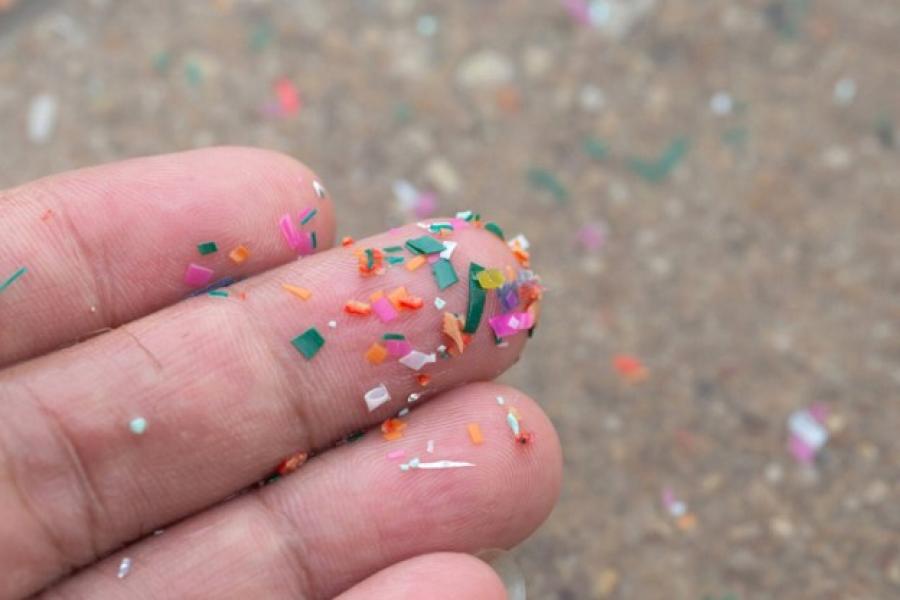 mano con micro plásticos en arena