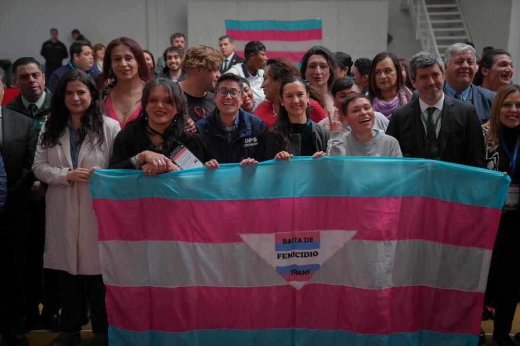 Un gran grupo de personas sostienen una bandera con el lema "Basta de Femicidio Trans", mostrando solidaridad y protestando contra la violencia contra las mujeres transgénero.