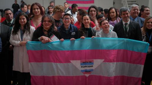 Un gran grupo de personas sostienen una bandera con el lema "Basta de Femicidio Trans", mostrando solidaridad y protestando contra la violencia contra las mujeres transgénero.